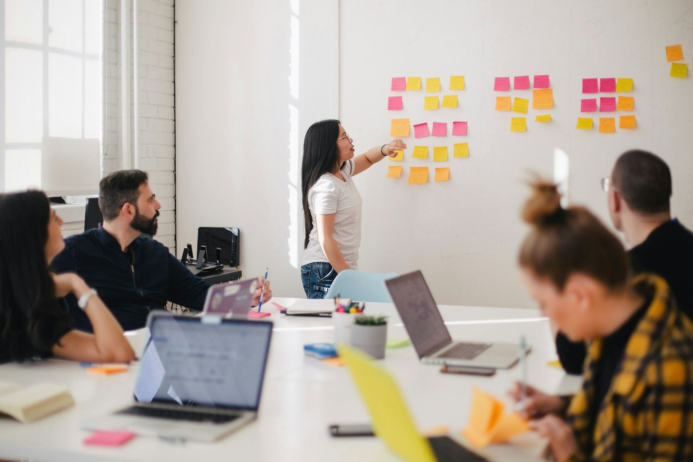 Riunione di lavoro con post-it alla parete per pianificare un progetto digitale