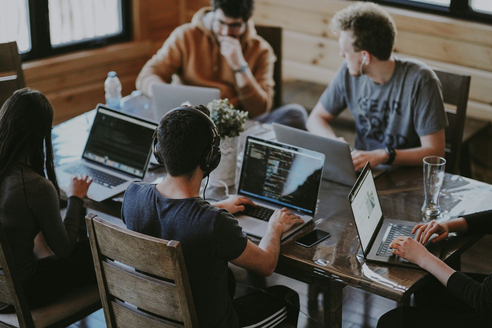 Team di professionisti digitali che lavora insieme su laptop attorno a un tavolo luminoso