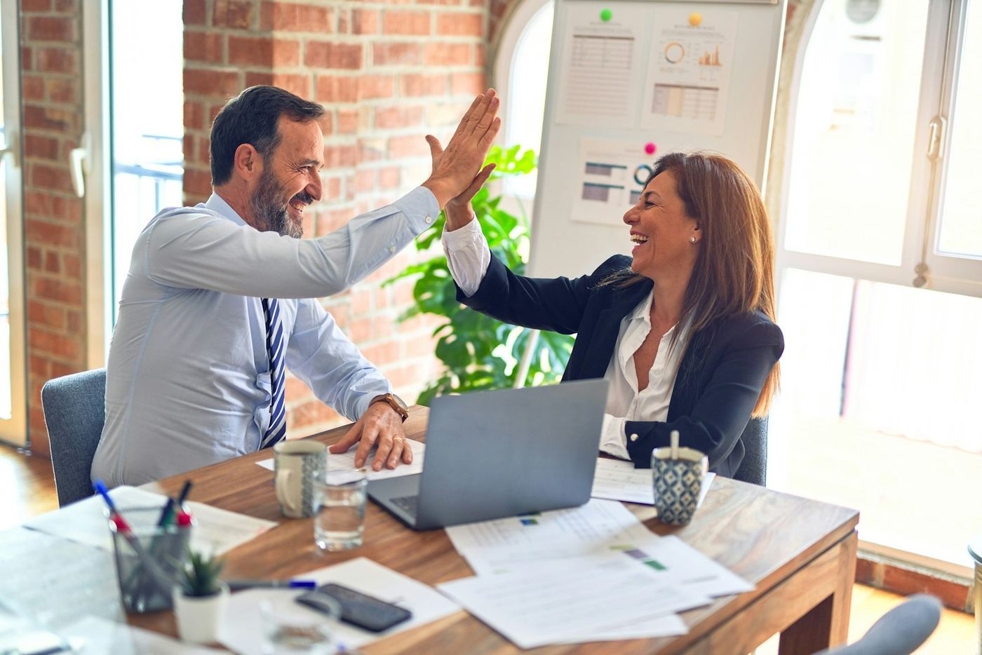 Due professionisti si salutano soddisfatti alla scrivania dopo un accordo di lavoro
